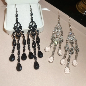 Detailed shot of retro palace style drop earrings in black and silver on velvet surface
