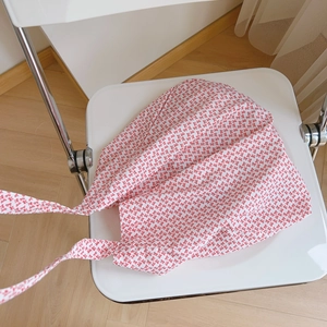 Détail du motif à nœuds rouges sur le sac en coton blanc léger posé sur une chaise