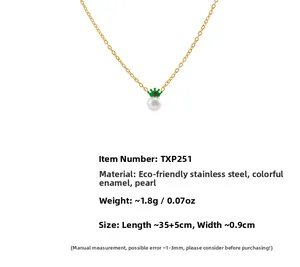Detailed view of gold crown pendant necklace with shell pearl and green enamel decor