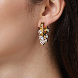 Detail of gold tassel earrings with faceted white zircons worn on ear for elegant style