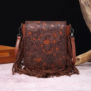 Detailed view of bohemian crossbody bag featuring floral embossing and long leather fringes