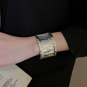 Detail of silver irregular wavy cuff bracelet with mirror finish on black suit wrist