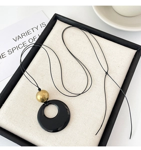 Detail of faux agate ring pendant necklace with golden bead on linen display board