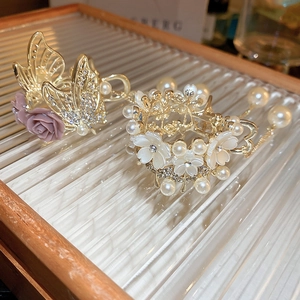 Detailed view of luxury gold hair claws with rose accents, pearls, and crystal tassels