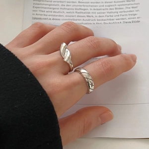 Macro detail of 925 sterling silver knotted ring and textured band on book background