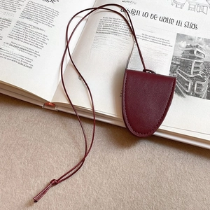 Macro shot of burgundy leather key holder with embossed V logo and matching lanyard strap