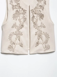 Close-up of beige suede vest featuring intricate 3D ribbon floral embroidery and texture