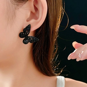 Close-up of black hollow butterfly earrings featuring sparkling zircon inlay on ear