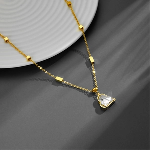 Minimalist gold heart pendant necklace with clear crystals on a textured white plate