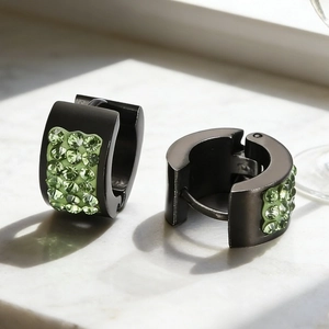 Macro detail of black plated hoop earrings with light green rhinestones on marble