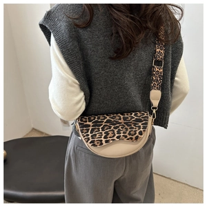Detailed view of beige saddle bag with leopard print strap and golden metal buckle