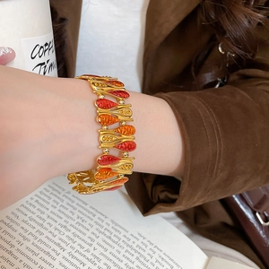 Close-up of a vintage gold-plated drop-link bracelet with red and orange enamel inlay