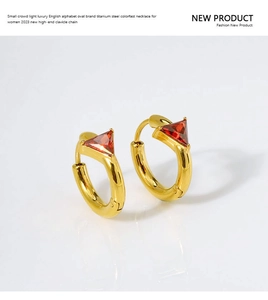Detail of gold titanium steel hoop earrings featuring inlaid red triangle crystals