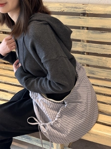 Detail of grey checkered nylon tote with drawstring side and large capacity on a model