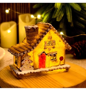 Detail of a glowing Christmas resin house with warm LED lights and festive snow texture