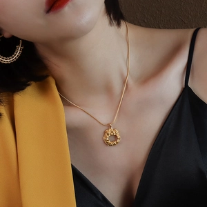 Textured round gold pendant necklace and earring set worn by a model in a yellow blazer