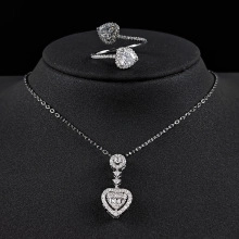 Close-up of heart-shaped necklace and ring set with clear crystals on a black display