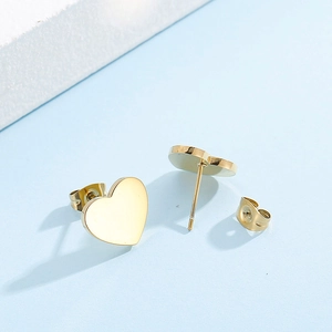Vue détaillée de boucles d'oreilles cœur dorées sur un fond minimaliste bleu et blanc