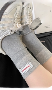Detail of grey ribbed mid-calf socks with woven label and vertical texture design