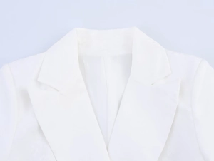 Close-up detail of white double-breasted blazer collar showing fabric texture and tailoring