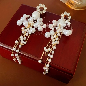 Detail of floral crystal studs and elegant white pearl tassels on gold metal chains