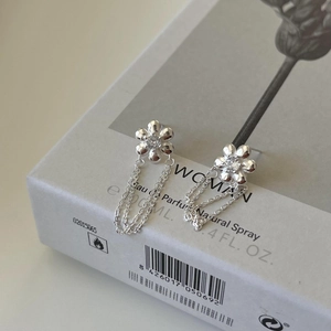 Detailed macro view of silver flower earrings with zircon center and delicate chain tassels