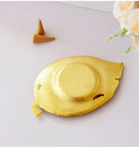 Detailed macro view of a golden leaf-shaped metal incense burner with textured surface