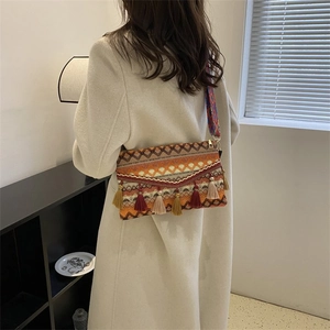Detail of bohemian woven crossbody bag with colorful tassels and patterned strap