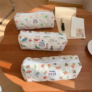 Close-up of quilted cotton pencil cases with floral and animal prints on a wooden table
