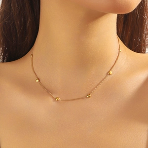 Close-up of minimalist gold-plated stainless steel chain necklace with heart beads on model