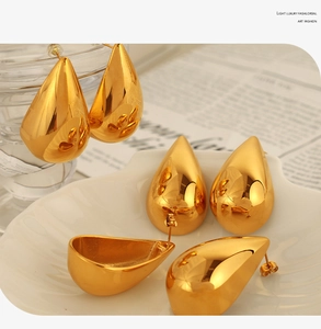 Close-up of golden teardrop earrings with mirror finish on a white shell tray