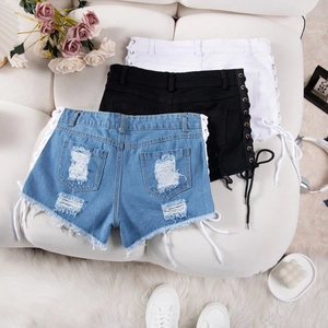 Dettaglio degli shorts in denim con lacci in anelli di metallo e trama strappata
