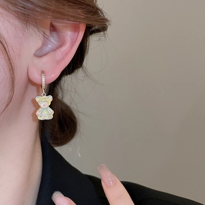 Gros plan de boucles d'oreilles ours nacré avec anneaux dorés sertis de zircons portées