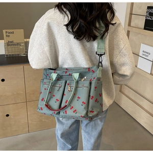 Close-up of printed tote bag with cherry pattern and red handle on model back