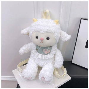 Detail of white plush sheep backpack with green floral bib on a book against white wall
