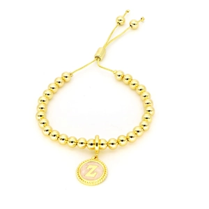 Gros plan d'un bracelet en perles plaqué or 18 carats avec pendentif rond lettre Z rose