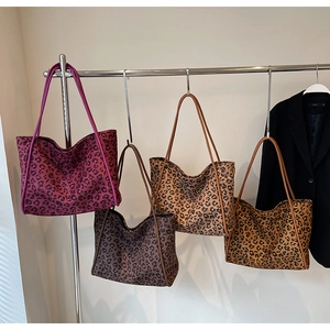 Multiple colors of leopard print tote bags hanging on a display rack in a showroom