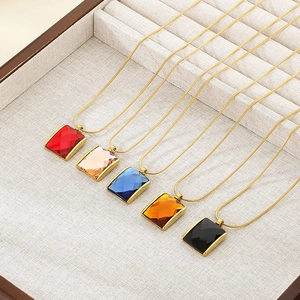Detail of colorful rectangular gemstone pendants with gold snake chains in a jewelry box