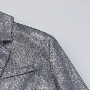 Detail of silver sequin blazer lapel showing high-shine metallic texture and fabric