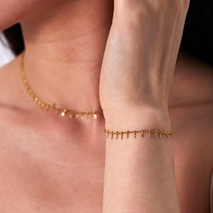 Detail of 18K gold plated tassel chain necklace and bracelet set on a model skin