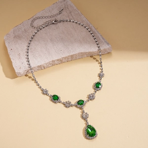 Detail of luxury necklace with emerald green crystals and teardrop pendant on stone
