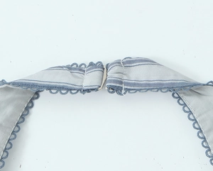 Detail of blue and gray striped knit fabric featuring wavy lace edges and metal hook closure