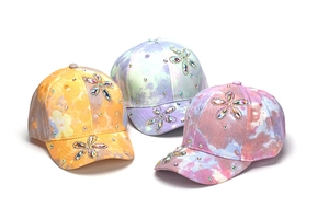 Dettaglio dei cappellini da baseball tie-dye per bambini con fiori di strass lucidi