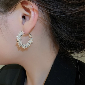 Close-up of model wearing silver irregular hoop earrings with pave-set rhinestones