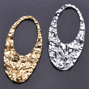 Macro detail of gold and silver irregular teardrop hollow pendants with hammered texture