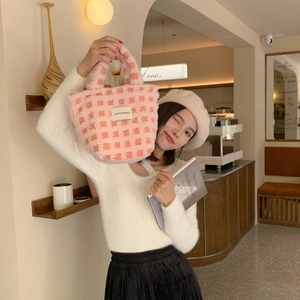 Detail of pink and white checkered plush tote bag with brand label in a cafe setting