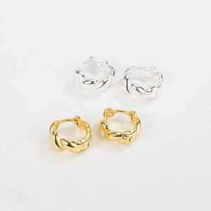 Dettaglio di orecchini a cerchio intrecciati in finiture argento e oro lucido