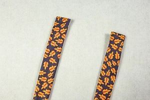 Macro detail of autumn maple leaf print on purple fabric straps for halter neck dress