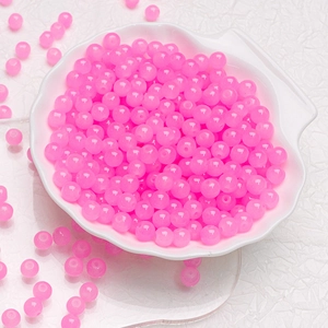 Close-up of translucent pink round glass beads in a white shell-shaped dish for DIY jewelry