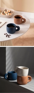 Collage of matte ceramic coffee mugs in deep blue, brown and cream on a marble surface